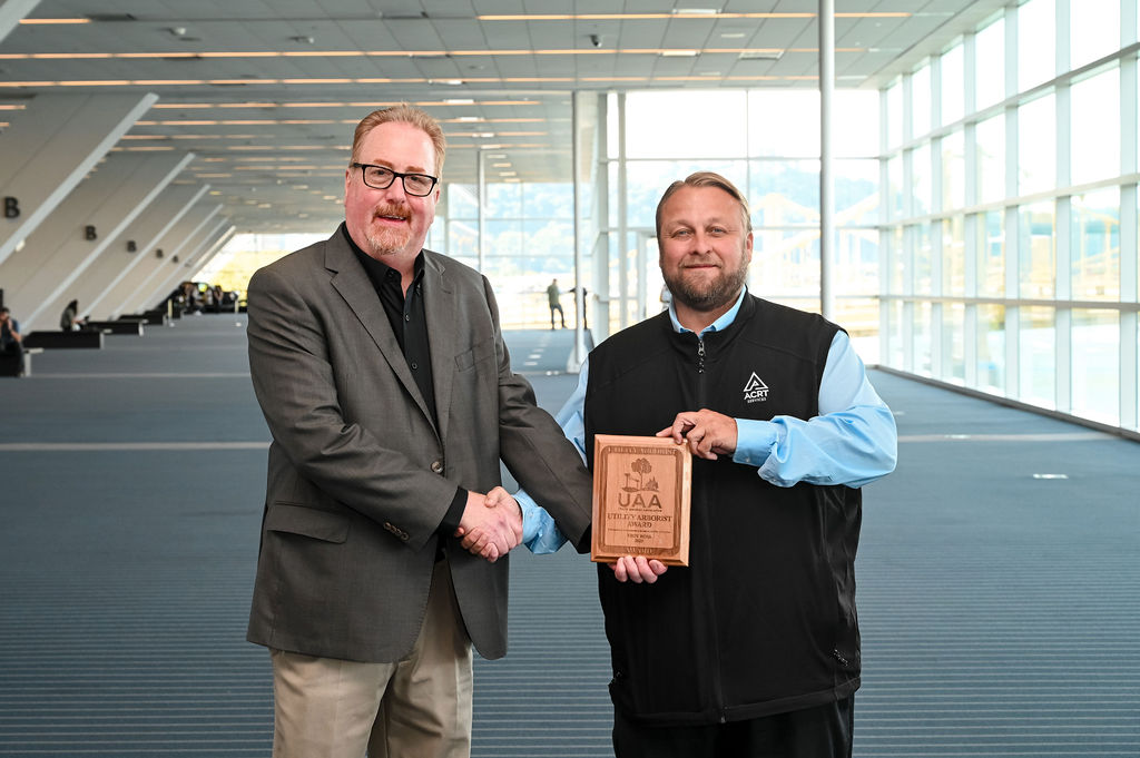 Two men standing together indoors smiling at the camera.