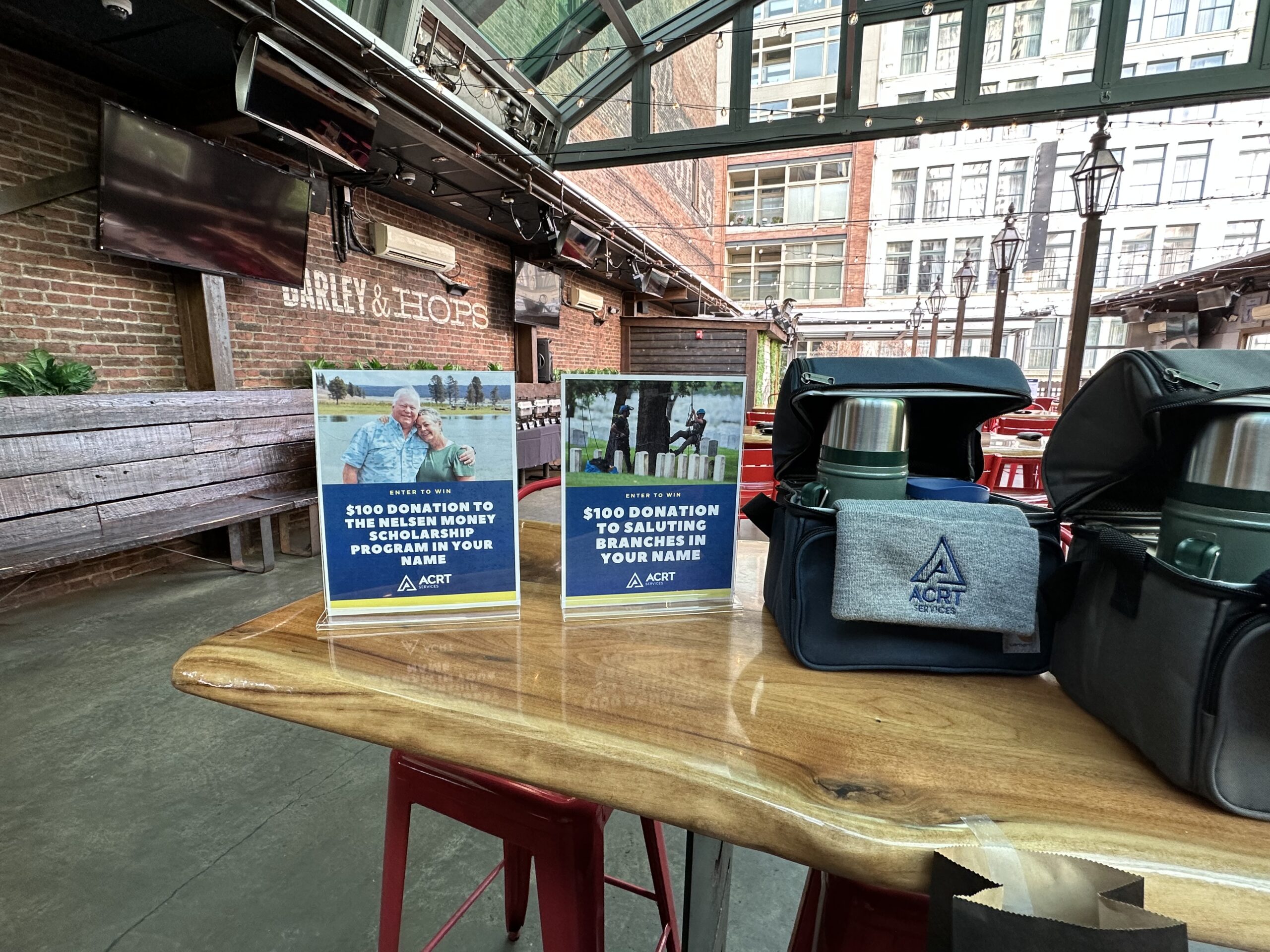 ACRT display table with donation signs and branded bags set up at an indoor event venue.
