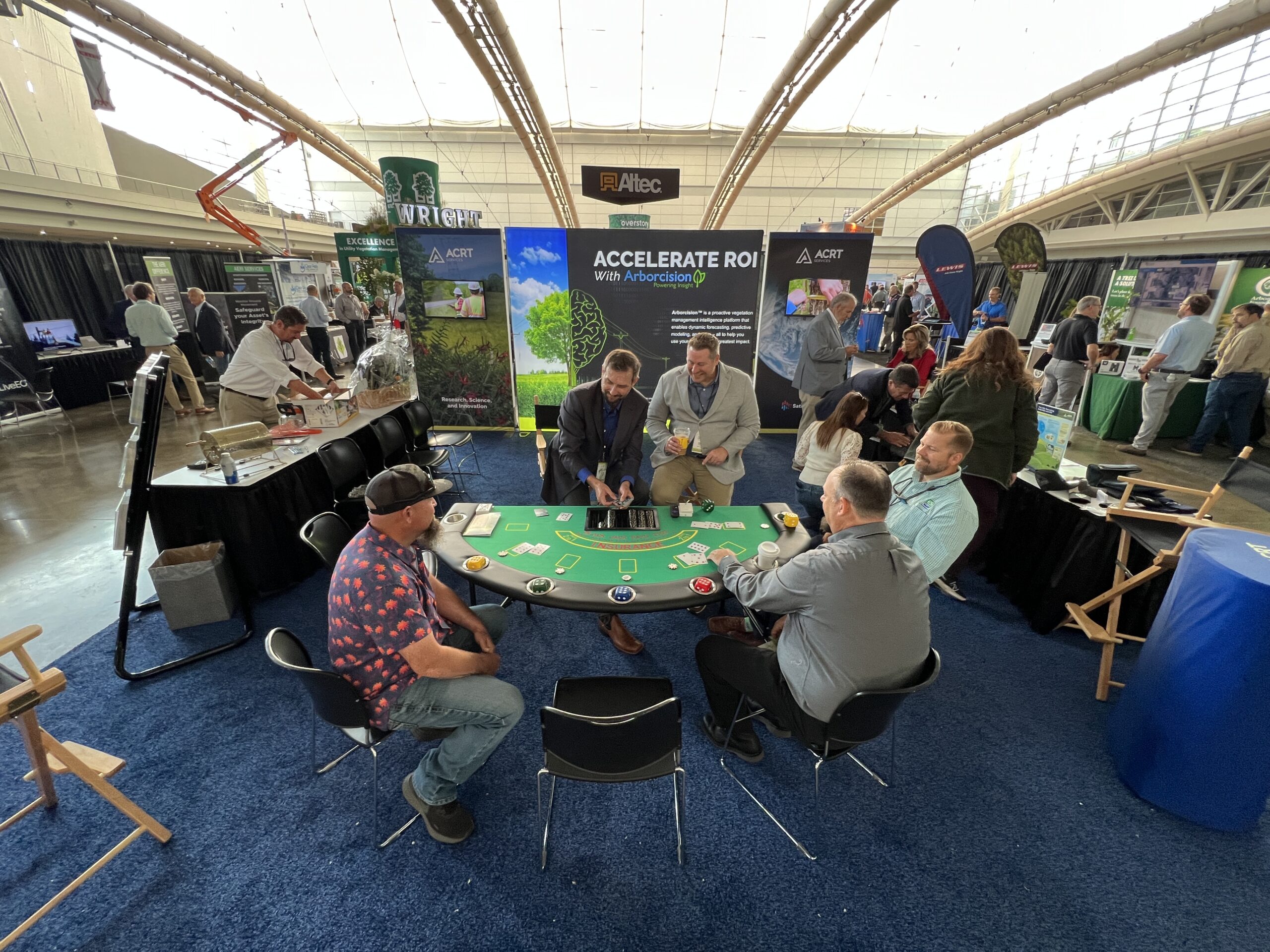 Attendees gather around a blackjack-style table at the ACRT booth during a trade show.