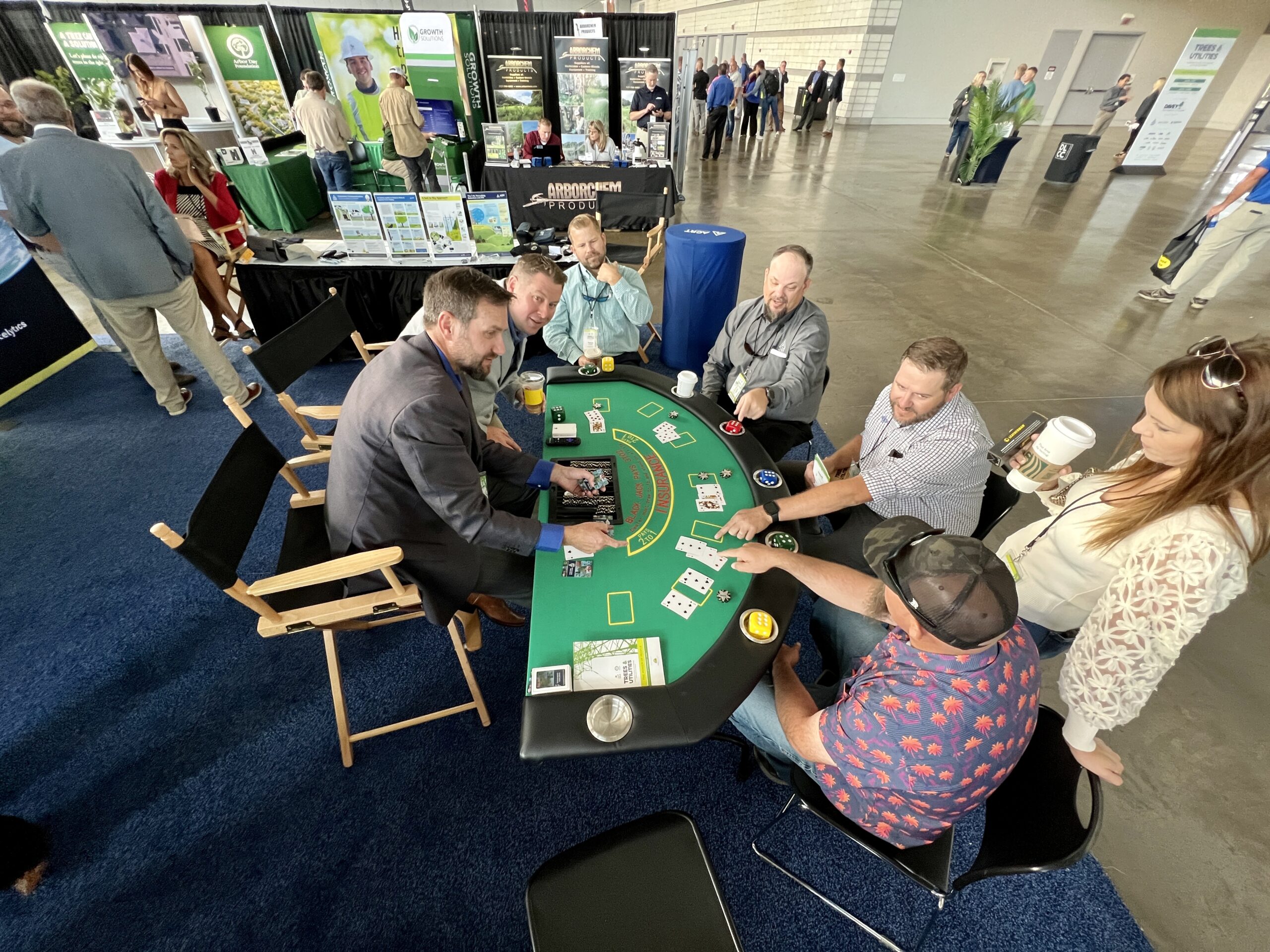 Attendees play a blackjack-style game at an exhibitor booth during a trade show.