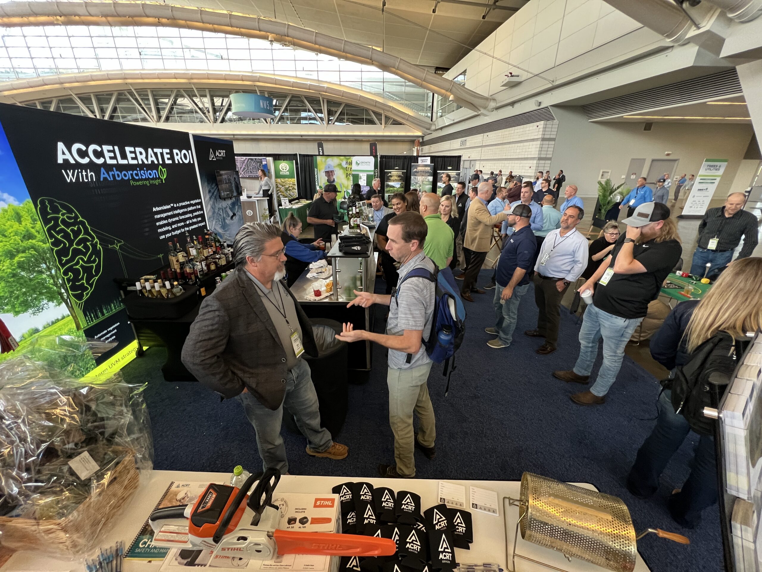 Attendees gather and network at the ACRT booth during a trade show, with branded displays and raffle items visible.