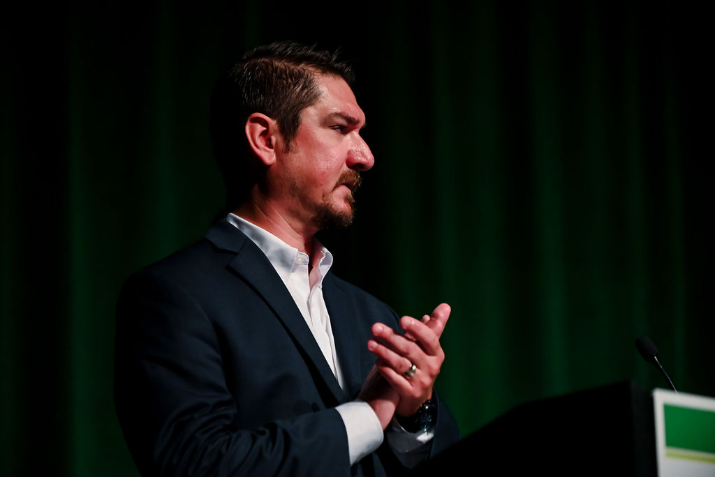 John Wasmer, executive vice president at ACRT Services, clapping during a presentation at an industry event.